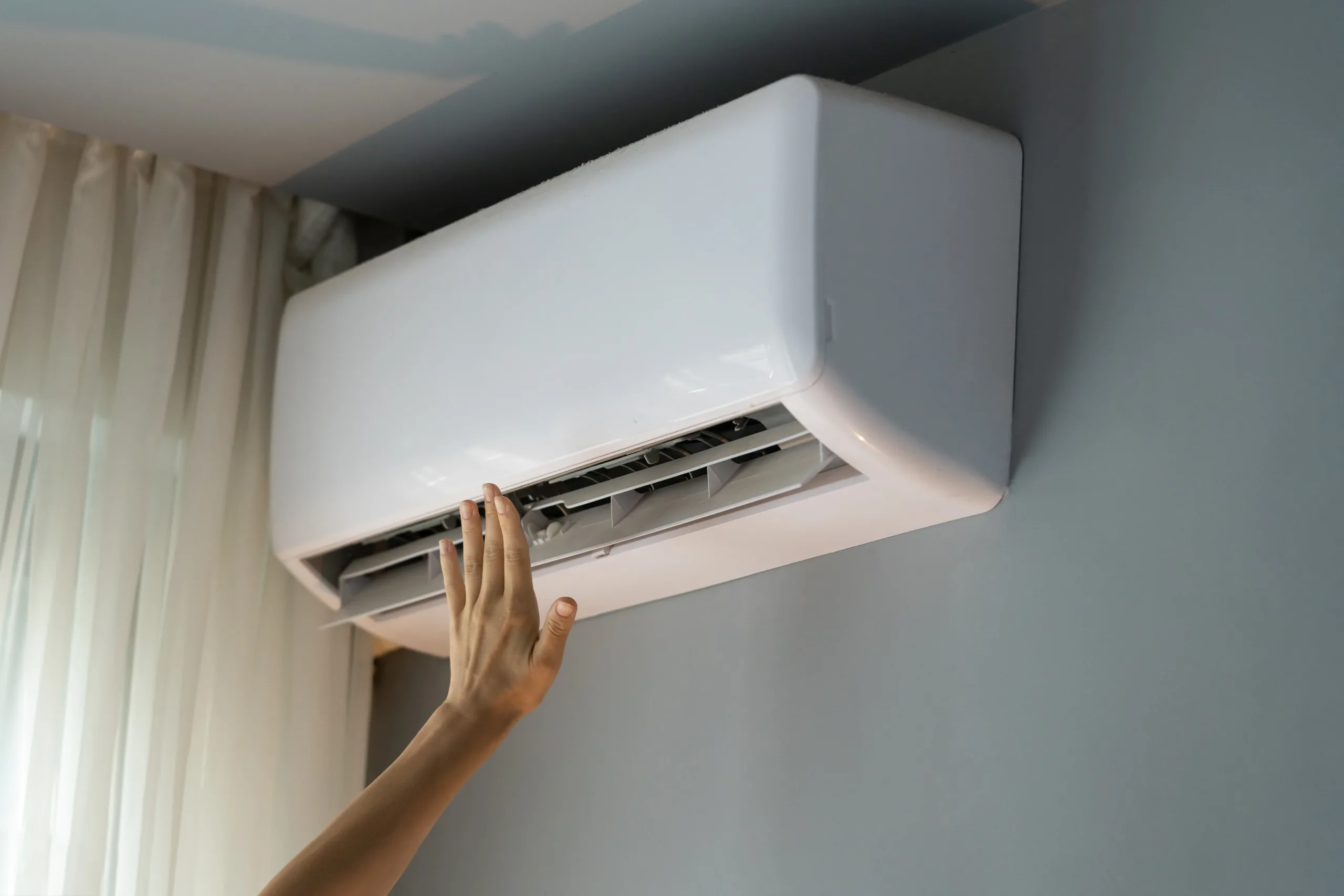 person with hand up to wall mounted ac